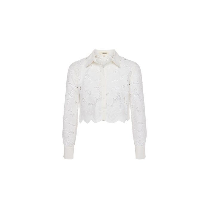 Seychelle Cropped Eyelet Blouse—white long-sleeve cropped blouse featuring visible floral eyelet lace patterns, a scalloped hem, button-down front, and classic collar. Displayed on a plain white background.