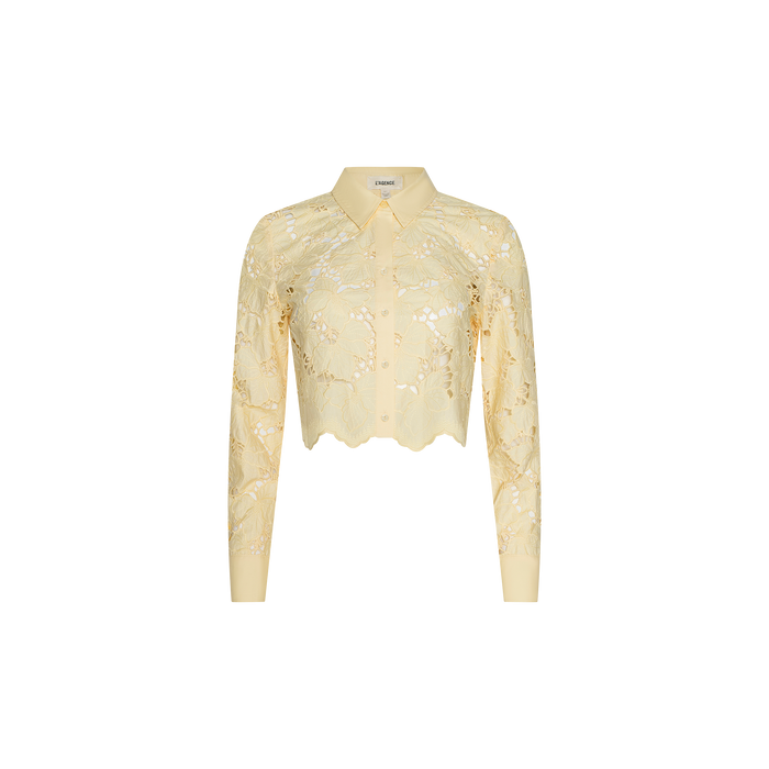 The Seychelle Cropped Eyelet Blouse is a light yellow, long-sleeve sheer poplin lace blouse featuring a collared neckline, cropped cut, and scalloped hem, displayed on a plain white background.