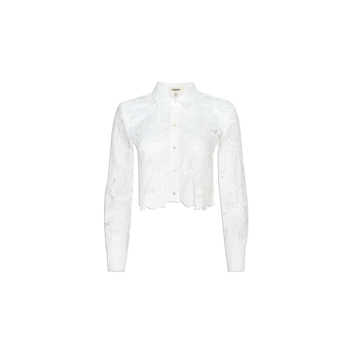 The Seychelle Cropped Eyelet Blouse is a white long-sleeve top featuring a floral lace pattern and a cropped cut hem, displayed on a plain light background.