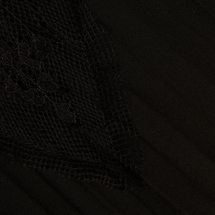 Close-up of the Sharon Cover-Up Pant in black, featuring a textured, triangular sheer lace overlay with intricate floral patterns on the left side, layered over smooth fabric.