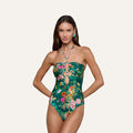 The model is wearing the Shiva One-Piece Swimsuit, featuring a green butterfly floral print, strapless neckline, and keyhole cutouts, as she poses with her hands on her hips against a plain background.