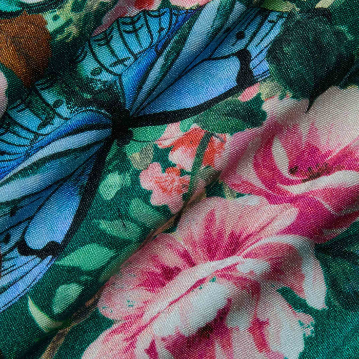The Shiva One-Piece Swimsuit showcases a vibrant butterfly floral print with blue butterflies and pink flowers, crafted from gently textured fabric with a softly creased appearance.