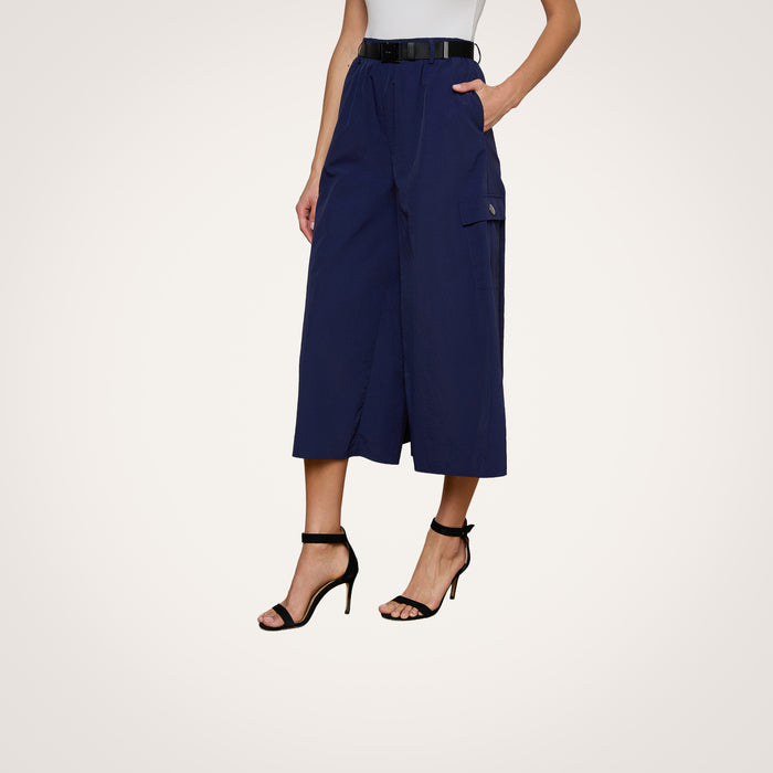 A person wearing the Shoda Cropped Wide-Leg Pant in navy blue with a black belt and black high-heeled sandals, standing against a plain light background.