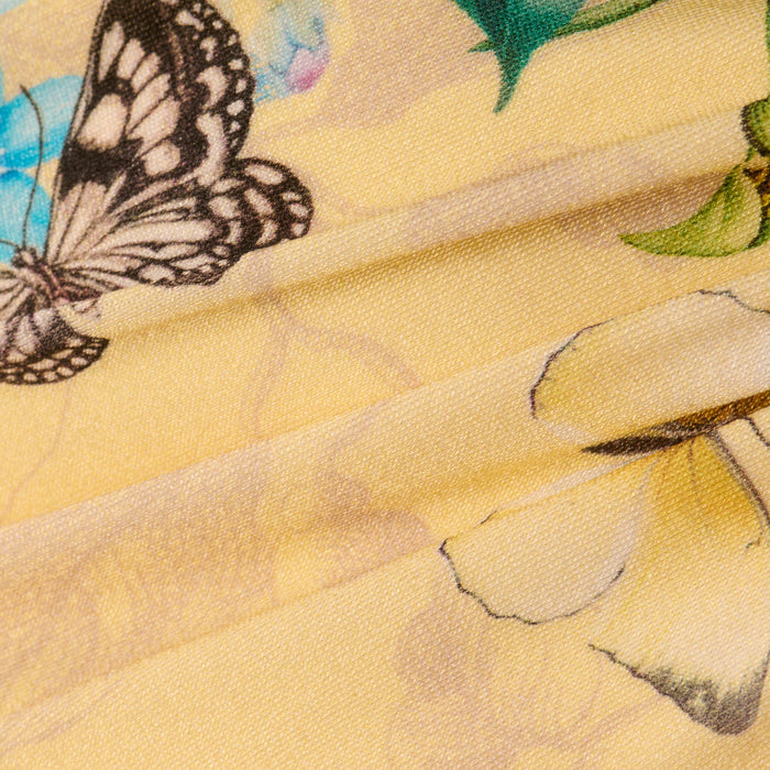 Close-up of the Sirena Bikini Top, featuring yellow fabric with a butterfly print, blue and yellow flowers, and visible folds in the material.