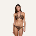 A woman wearing the Sirena Halter Bikini Top with leopard print and matching side-tie bottoms, standing against a plain, light-colored background.