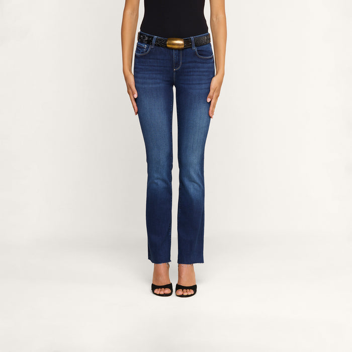 A person wearing a black sleeveless top, the Sneeki Low-Rise Straight-Leg Jean in a dark wash with a black belt, and black open-toe heels stands against a plain white background.
