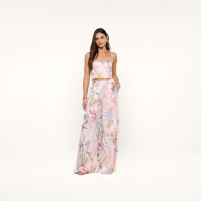 A woman wearing the Sonya Bustier in a pink palm leaf print with matching wide-leg pants, standing against a plain white background.