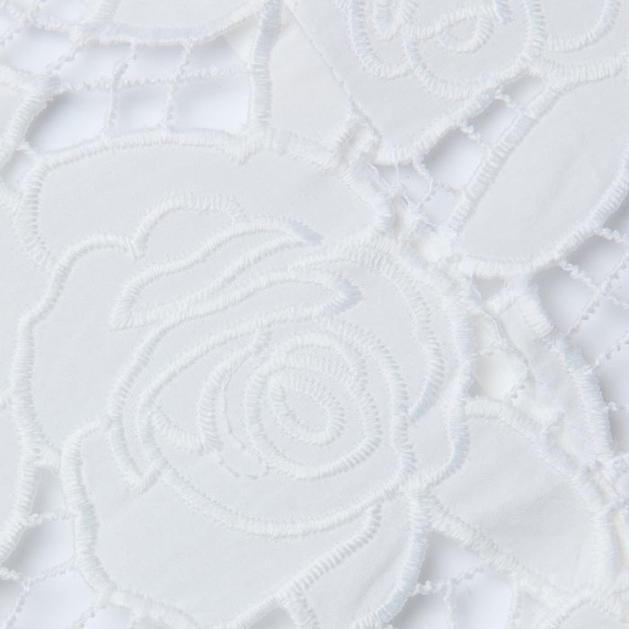 Close-up of the Sonya Bustier, featuring white lace fabric with an intricate floral rose pattern, showcasing delicate embroidery and openwork details reminiscent of a cotton bustier top with underwire cups, all set against a white background.