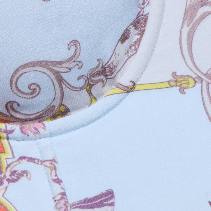 Close-up of the Sonya Bustier, crafted from lightweight twill with a light blue background adorned with decorative brown, purple, and yellow patterns. Swirling designs and ornate shapes evoke a baroque toile print, while visible stitching accentuates the curved seam.