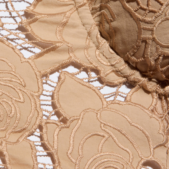 Close-up of beige floral lace fabric from the Sonya Bustier, showcasing intricate embroidered flower patterns and open mesh sections against a white background, reminiscent of the delicate detailing often found on a bustier top.