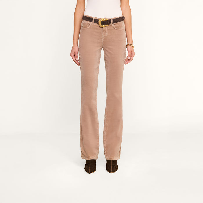 A person wearing the Stevie Velvet Jean styled in a high rise fit, paired with a white top, a brown belt, and dark brown shoes, stands against a plain white background. The image highlights the outfit from shoulders to feet.