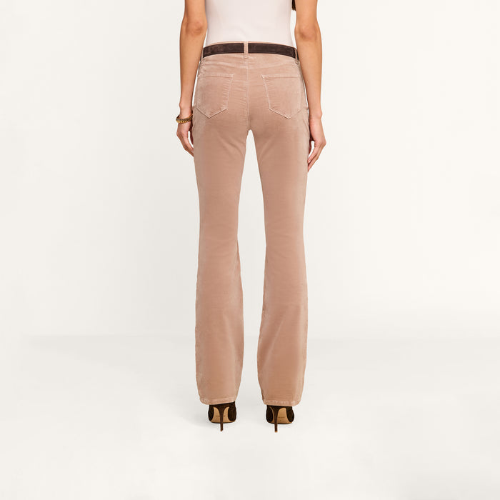 A person is shown from the back, wearing high-heeled shoes and the Stevie Velvet Jean in light brown, standing against a plain white background.