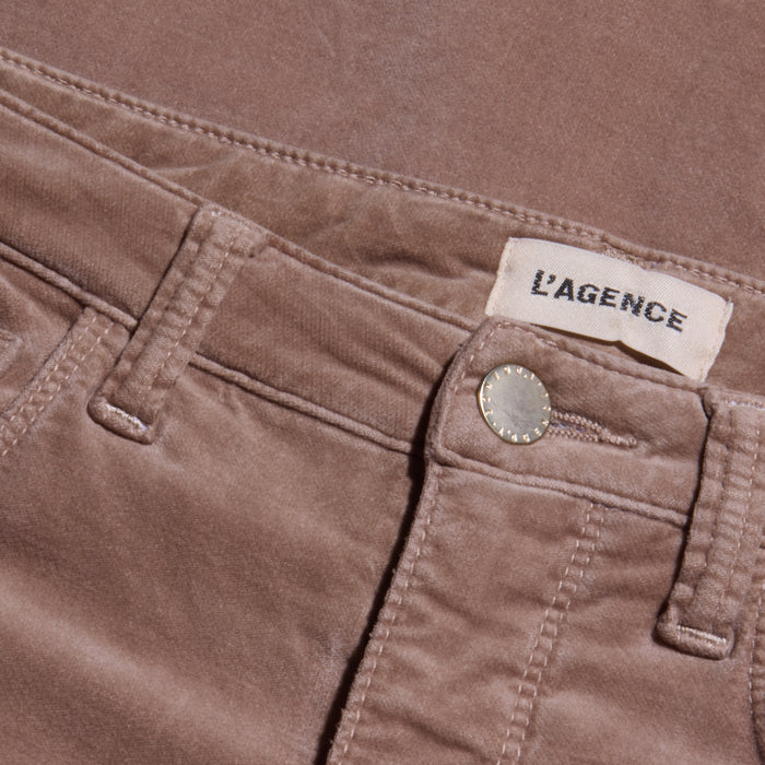 Close-up of the Stevie Velvet Jean in mauve stretch velvet, showcasing a visible waistband, metal button, belt loops, and a sewn white L’AGENCE label.