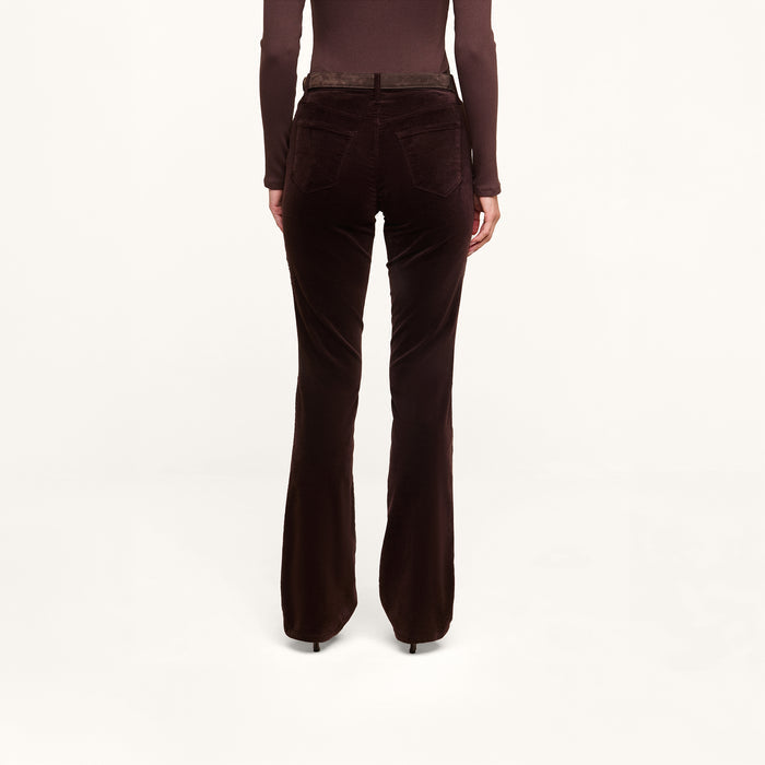 A person is shown from the back, standing against a plain white background, wearing the Stevie Velvet Jean in dark java brown—a stretch velvet pant with a slim straight leg—paired with a matching long-sleeve top.