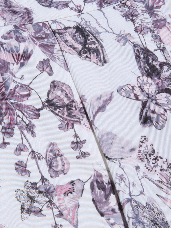 Close-up of the Sylie Short’s fabric, showcasing a delicate and intricate pattern of butterflies and flowers in shades of purple, pink, and gray on a white background. Pleats enhance the texture of the soft material, while an elasticized waistband completes the butterfly print design.