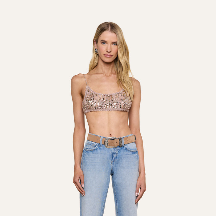 A woman wearing the Taline Crocheted Bralette and light blue jeans with a beige belt stands facing forward against a plain background.