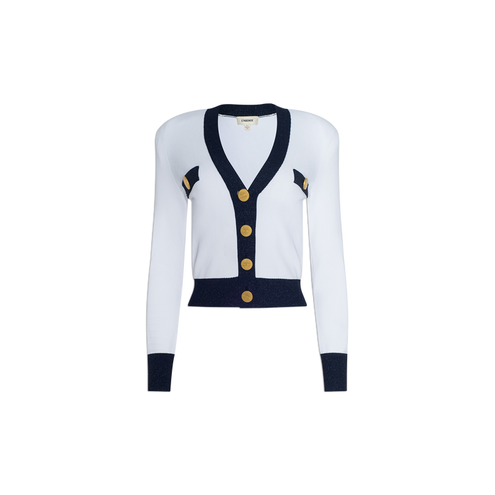 Introducing the Taya Cardigan: a Parisian-inspired white sweater featuring metallic trim, gold buttons, and navy blue accents on the shoulders and cuffs. Designed with a deep V-neckline and cropped silhouette for an effortlessly chic look.