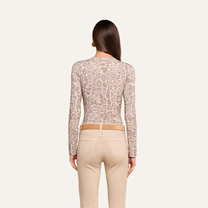 A woman stands with her back to the camera, wearing the Tess Long Sleeve Tee in a slim fit grey leopard print, paired with beige pants and a brown belt. Her straight hair falls past her shoulders against a plain, light background.