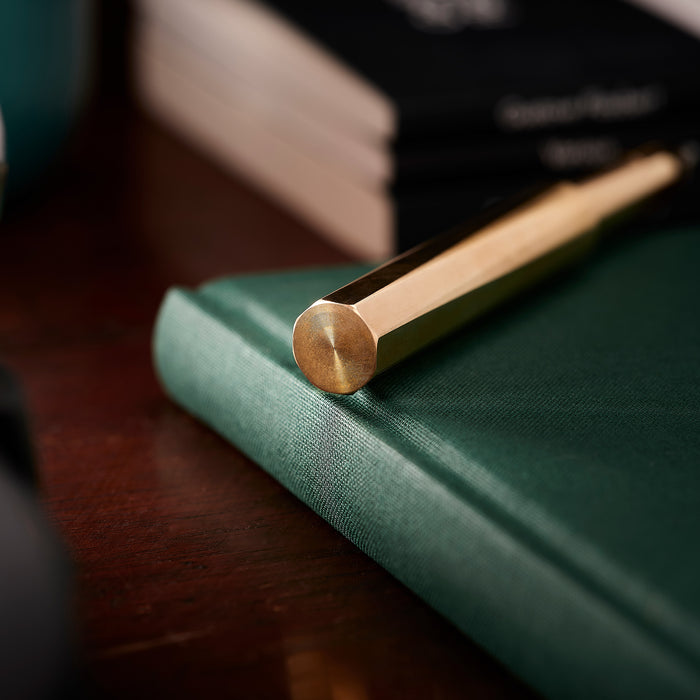 Close-up of the end of the Brass Wren lid, highlighting its solid octagonal brass lid on a green notebook.