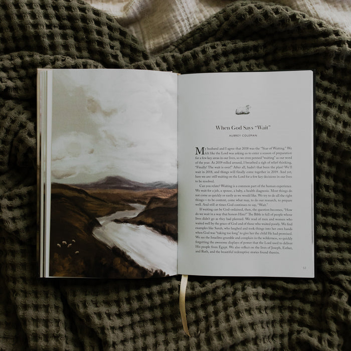 The Good Shepherd opened to the When God say "Wait" page laying on a green waffle styled blanket on another creme blanket