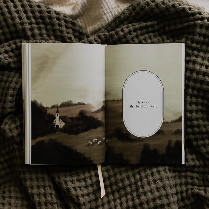 The Good Shepherd opened to the a full page devotional, laying on a green waffle styled blanket on another creme blanket