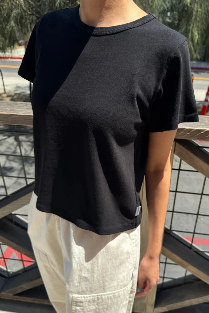 Person wearing a black t-shirt and light-colored pants standing on a metal staircase.