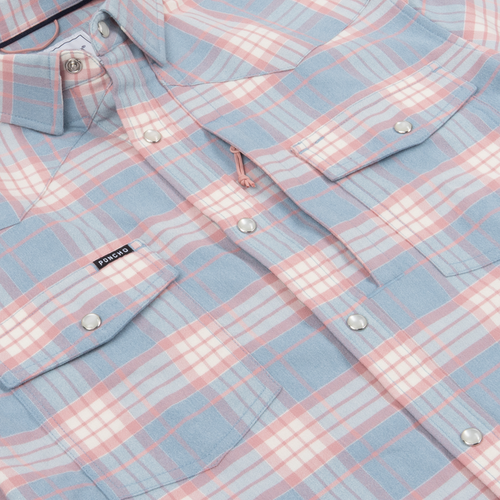 Close-up of a soft plaid button-up shirt in pastel blue and pink tones called The Pacific City, highlighting snap pockets.