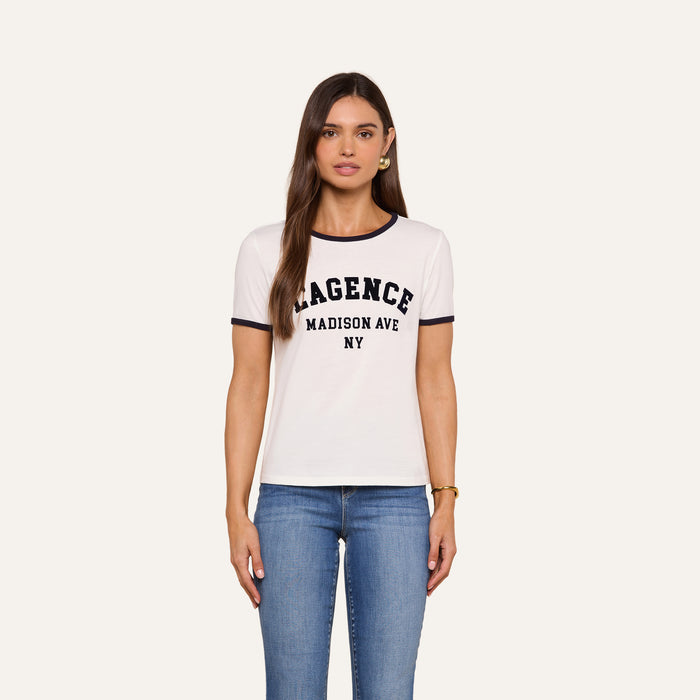 Woman with long brown hair wearing a relaxed fit Tommie Crewneck Tee made from Supima cotton and blue jeans, standing in front of a plain light background.