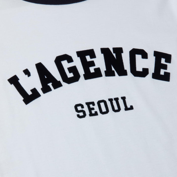 The Tommie Crewneck Tee is a relaxed fit white ringer tee crafted from Supima cotton, featuring bold black “LAGENCE” lettering across the front with “SEOUL” printed in smaller letters underneath.