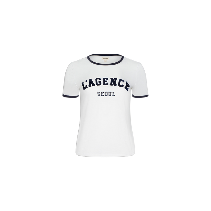 The Tommie Crewneck Tee is a white short-sleeve ringer shirt with black trim on the collar and sleeves. Made from soft Supima cotton for a relaxed fit, it features bold black “LAGENCE” text above “SEOUL” on the front. Displayed against a plain white background.
