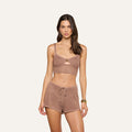 A woman wearing the Tracy Bralette Top in a matching brown pointelle knit set with shorts, standing against a plain light background in a relaxed pose with minimal accessories.