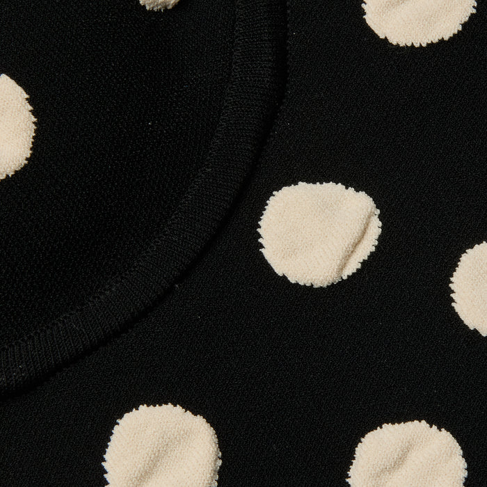 Close-up of the Tula Knit Bra Top in black, showcasing large, textured jacquard polka dots and a visible seam curving through the upper left portion of the fabric.