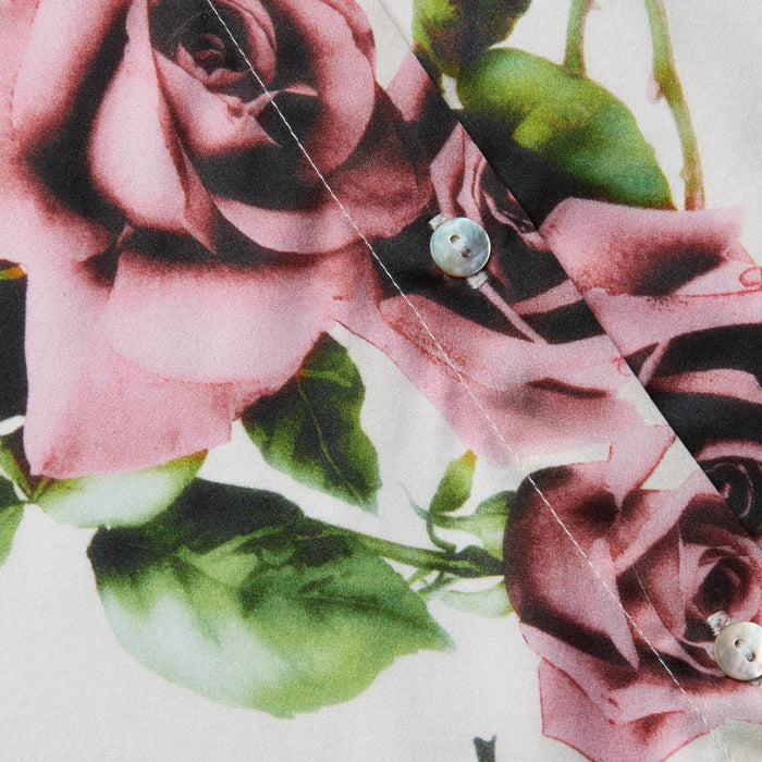 Close-up of the Tyler Silk Blouse, showcasing its mauve rose and green leaf print, visible white buttons, and detailed stitching on the long sleeves.