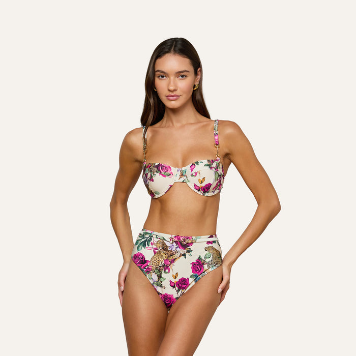 A woman stands against a plain, light background wearing the Vanessa High-Waisted Bikini Bottom in rose leopard print, featuring UPF 50 protection.