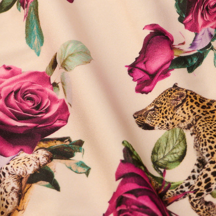 The Vanessa High-Waisted Bikini Bottom showcases a playful blend of pink roses and green leaves intertwined with leopard heads and legs, all set against a light beige background. This unique bikini bottom features an artistic rose leopard print that fuses floral and animal motifs for a colorful, stylish look.