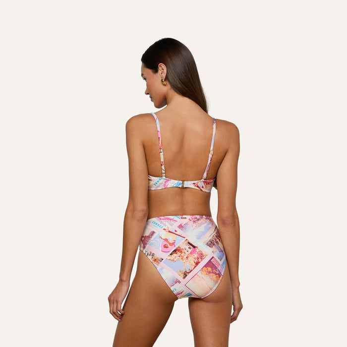 Woman with long brown hair wearing the Vanessa High-Waisted Bikini Bottom in a postcard print, shown from the back against a plain light background.