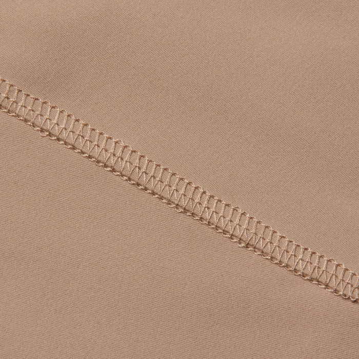 Close-up of beige fabric from the Velle Knit Panty, featuring a high waist design with a visible overlock stitch seam running diagonally, highlighting the intricate threadwork and smooth textile texture.