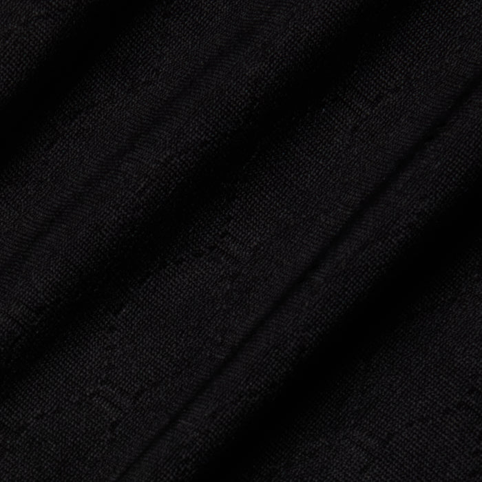 Close-up of the Violet String Bikini Bottom’s black fabric, featuring a subtle textured pattern and diagonal folds that create shadows and highlights across the material.