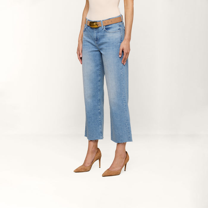 A person is wearing the Wanda Cropped Wide-Leg Jean in a light blue wash, paired with a beige sleeveless top, a brown belt, and tan high-heeled shoes, standing against a plain white background. The head is not visible in the image.