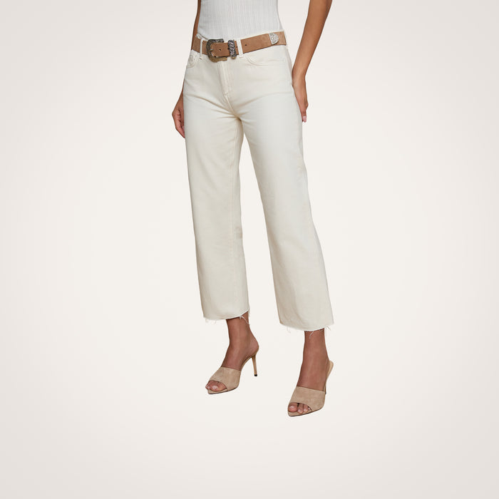 A woman models the Wanda Cropped Wide-Leg Jean in off-white, styled with a brown belt, a white ribbed sleeveless top, and beige heeled sandals. The image is set against a plain light background, and the woman’s head is not visible.