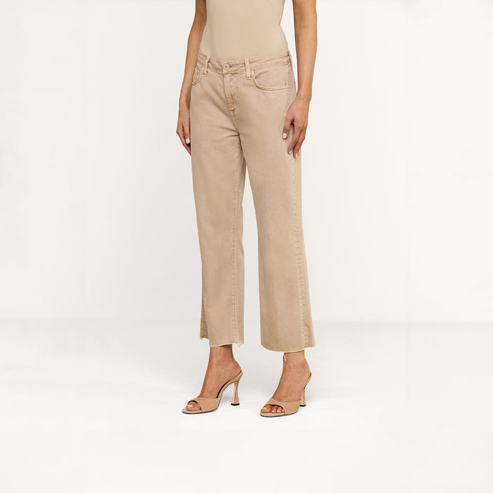 A person stands against a plain white background, showing only the lower half of their body while wearing the Wanda Cropped Wide-Leg Jean in a neutral tan shade, paired with a beige sleeveless top and beige open-toe heels.
