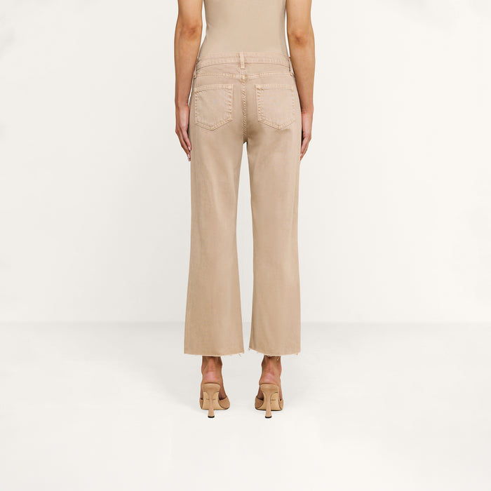 A person wearing Wanda Cropped Wide-Leg Jeans in a neutral tan color and heeled sandals, shown from the back, standing against a plain white background.
