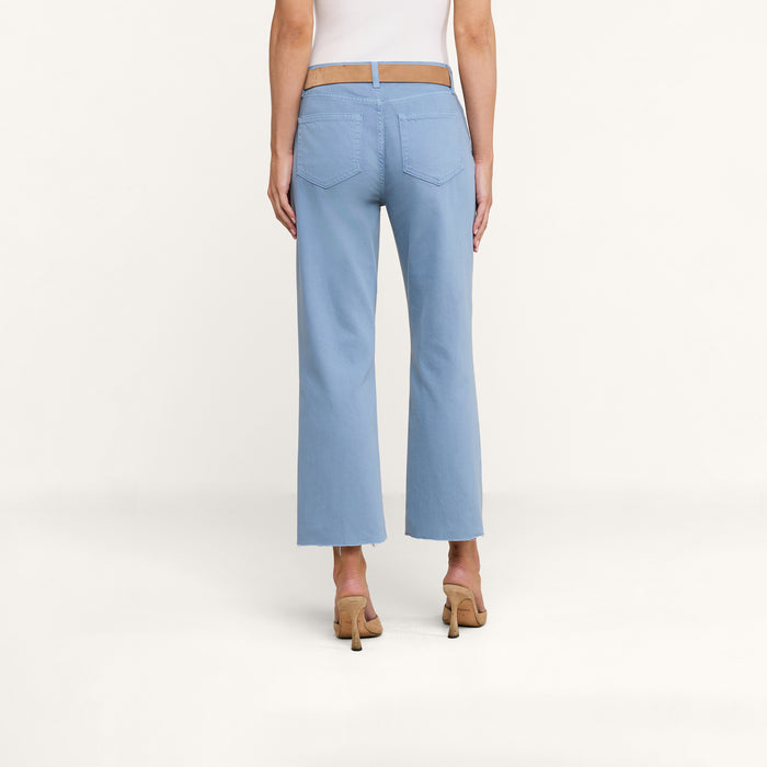 A person is shown from the back wearing the Wanda Cropped Wide-Leg Jean in light blue denim paired with beige heels, standing against a plain white background and evoking effortless Parisian style.