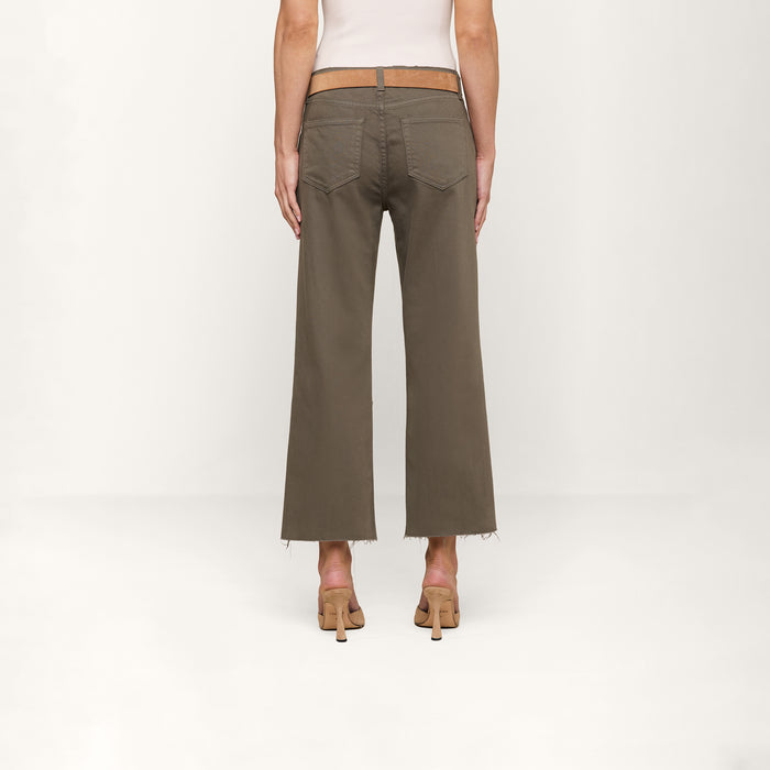 A person wearing a white top, the Parisian style Wanda Cropped Wide-Leg Jean in olive green with frayed hems, and beige heeled sandals stands facing away against a plain white background.