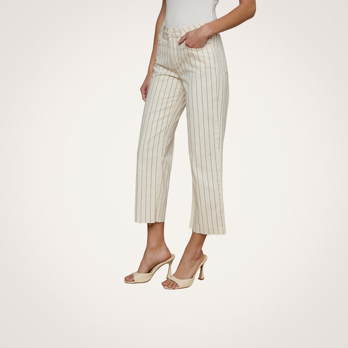 A woman wearing a white sleeveless top, the Wanda Cropped Wide-Leg Pant in cream-colored cotton twill with nautical stripes, and beige high-heeled sandals stands against a light background.