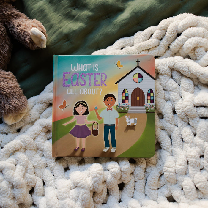 What is Easter All About Kids Book cover page laying on a cream colored blanket and a green blanket