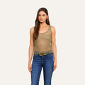 A woman with long brown hair wearing the sheer, sleeveless Zia Tank in gold, paired with blue jeans and a belt, stands facing forward against a plain light background.