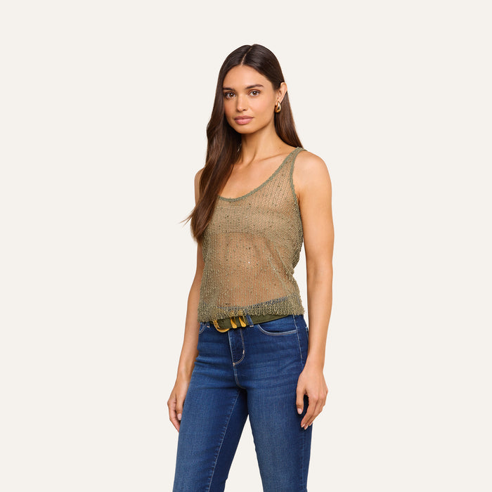 A woman wearing the Zia Tank, a mesh knit sleeveless top, and blue jeans stands against a plain light background, looking at the camera with a relaxed expression.