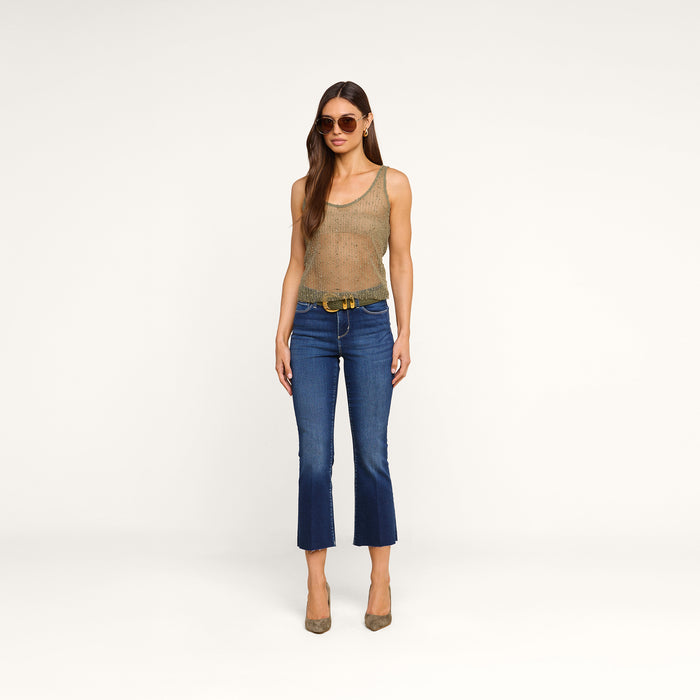 A person wearing the Zia Tank, sunglasses, blue cropped jeans, a belt, and heels stands against a plain white background.